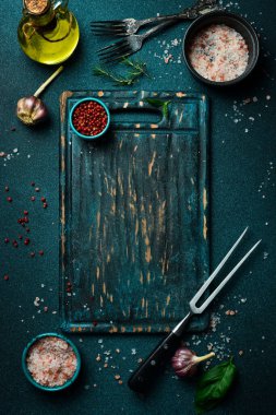 Koyu mavi arka planda tahta kesme tahtası. Mutfak aletleri. Düz yatıyordu