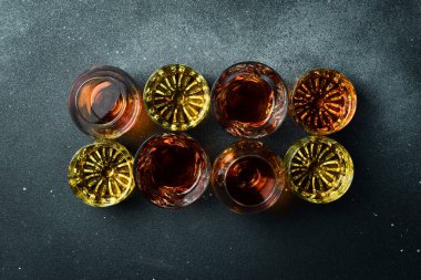 Sert alkollü içecekler, sert içkiler, alkollü içecekler ve taş bir masada damıtılıyor. Güçlü alkollü içecekler. Karanlık bir taş arka planda.