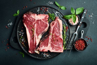 İki çiğ biftek ve taze otlar ve pişirmeye hazır. Bir parça dana eti..