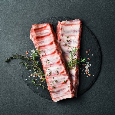 Biberiyeli, baharatlı ve otlu taze çiğ pirzola. Karanlık bir arka planda. Üst Manzara. Metin için boş alan.