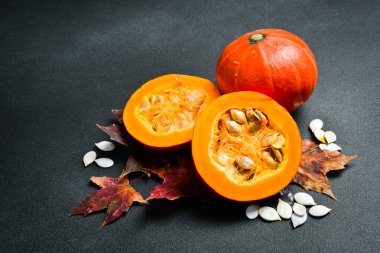 Organik taze portakallı kabak ve tohumlar. Sonbahar balkabağı yemeği. Karanlık bir taş arka planda.