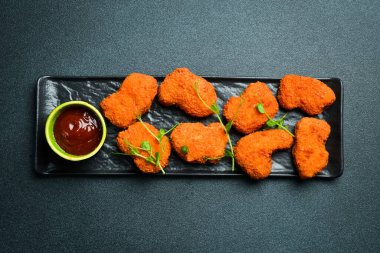 Siyah taş tabakta ketçap soslu tavuk nugget. Karanlık bir arkaplanda, yakın plan.