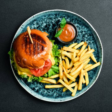 Geleneksel hamburger ve ketçaplı patates kızartması. Fast food. Karanlık bir arkaplanda, yakın plan.
