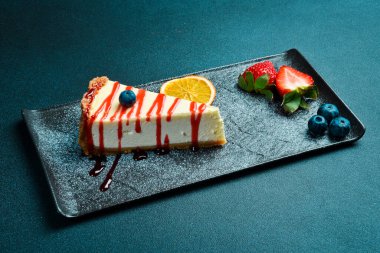 Çilek soslu ve yabanmersinli cheesecake. Tatlı. Karanlık bir arkaplanda, yakın plan.