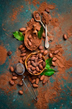 Tahta bir kasede kakao tozu ve kakao çekirdeği. Karanlık bir arka planda. Üst görünüm.