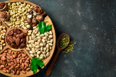 Tahta tabakta fındık çeşitleri. Üst Manzara. Tahta masada karışık fındık. Karanlık bir arka planda.