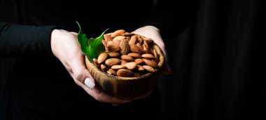 Tahta bir kasedeki bademler. Sağlıklı yüksek kalorili vejetaryen gıda konsepti. Siyah bir arkaplanda.