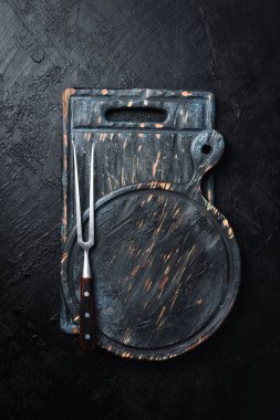 Ahşap kesme tahtasındaki ızgara için çelik çatal. Siyah bir tahta üzerinde. Üst görünüm.