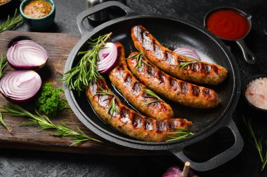 Izgarada, tavada pişmiş sulu sığır eti sosisi. Kapatın. Üst görünüm.