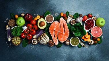 Sağlıklı yiyecekler temiz yemek seçimi: taze meyve, böğürtlen, süper yiyecek, fındık, balık ve mantar. Gri beton arka planda. Üst görünüm.