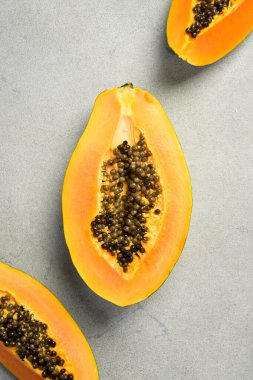 Egzotik papaya meyvelerini yakın çekim. Dilimlenmiş papaya gri beton arka planda.