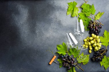Üzüm ve üzüm yapraklı şarap kadehleri. Gri taştan bir arka planda. Üst görünüm.