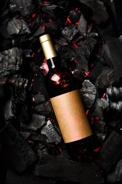 Kömürün arka planında şişe içinde beyaz şarap. Metin için boş alan. Üst görünüm.