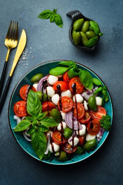 Taze yaz salatası: domates, mozzarella peyniri, fesleğen ve zeytin. Caprese. Gri beton arka planda.