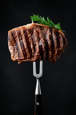 Biberiyeli biftek ve çatallı baharat. Izgara biftek. Siyah bir arkaplanda.