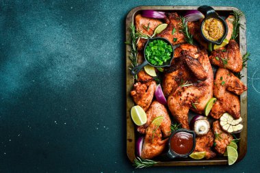 Metal tepside pişirilmiş tavuk ve tavuk kanatları. Kırsal tarzda. Karanlık bir arka planda.