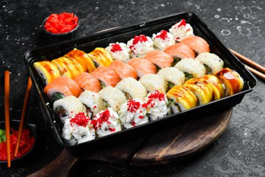 Peynirli ve balıklı suşi. Sushi teslimatı. Tek kullanımlık sofra takımı. Tahtada..