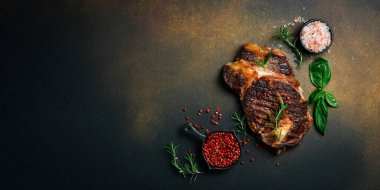 Koyu kahverengi arka planda biberiyeli ızgara dana biftek. Afiş fotoğrafı. Kopyalama alanı olan üst görünüm. Düz yatıyordu