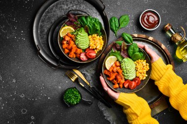 Buda çanağını tutan kadın eller: avokado, balkabağı, kiraz domatesleri, mısır ve marul. Diyet olsun. Sağlıklı dengeli beslenme.