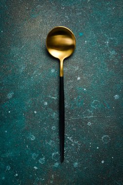 Metal antika masa kaşığı. Koyu yeşil turkuaz bir arka planda. Metin için boş alan.