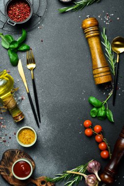 Mutfak afişi. Koyu taş bir masada çatal bıçak, sebze ve baharatlar. Metin için boş alan.