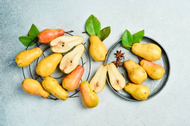 Gri masada yaprakları olan taze armutlar. Sonbahar meyveleri. Üst İnceleme.