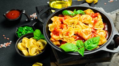 Koyu arkaplanda domates soslu ve fesleğenli Ravioli. Üst Manzara. İtalyan geleneksel mutfağı.