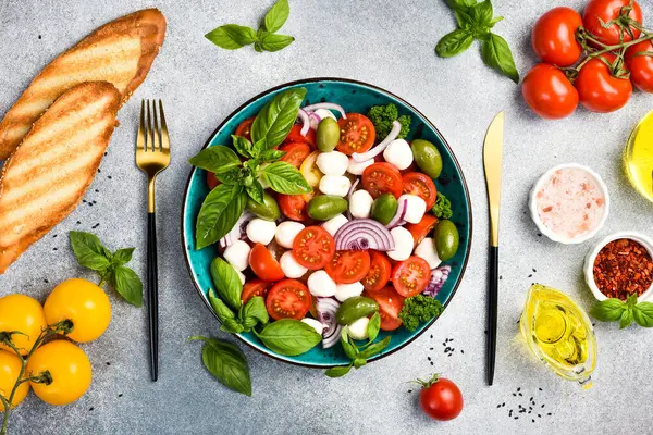 Bir kasede renkli salata: domates, mozzarella peyniri, fesleğen ve zeytin. Üst görünüm.