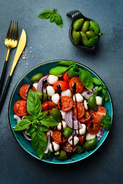 Taze yaz salatası: domates, mozzarella peyniri, fesleğen ve zeytin. Caprese. Gri beton arka planda.