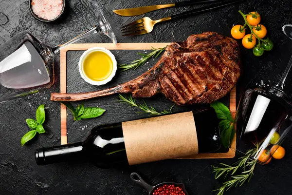 Şişe şarap, bardaklar ve biftek. Siyah Angus bifteği ve yıllanmış şarap. Üst görünüm.