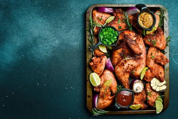 Metal tepside pişirilmiş tavuk ve tavuk kanatları. Kırsal tarzda. Karanlık bir arka planda.