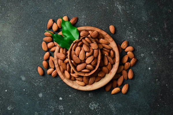 Tahta bir kasede fındık bademi. Sağlıklı atıştırmalıklar. Karanlık bir arka planda.