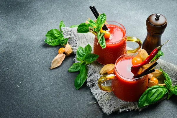 Baharatlı ve fesleğenli taze domates suyu. Koyu taştan bir masada..