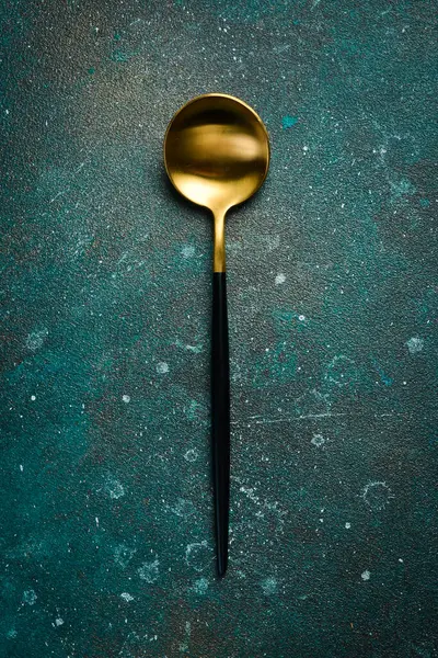 Metal antika masa kaşığı. Koyu yeşil turkuaz bir arka planda. Metin için boş alan.