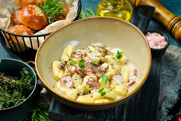 Pastırmalı ve ekşi kremalı patates gnocchi. Siyah taştan bir arka planda. Ekmek.