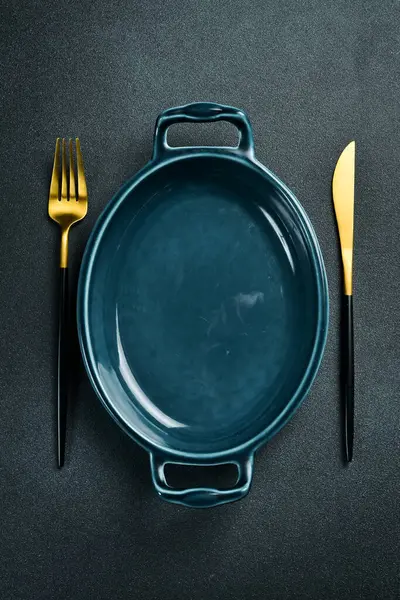 Yemek pişirmek için oval porselen form. Siyah taştan bir arka planda. Metin için boş alan.