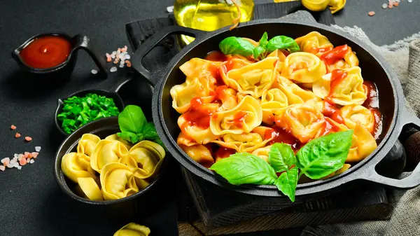Koyu arkaplanda domates soslu ve fesleğenli Ravioli. Üst Manzara. İtalyan geleneksel mutfağı.