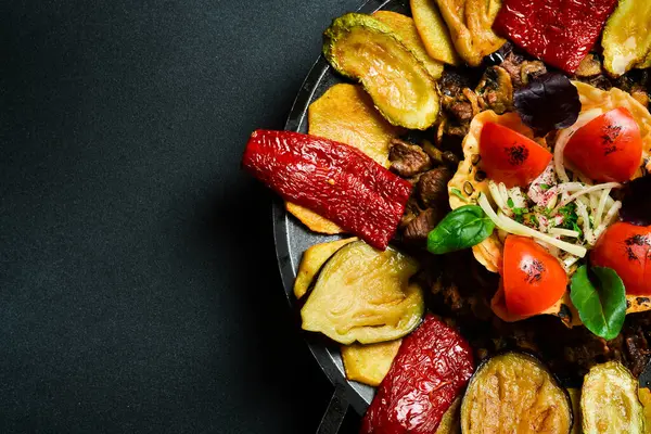 Saj - geleneksel Azerbaycan yemekleri. Metal bir tavada kuzu saj. Metin için boş alan. Karanlık bir arka planda.