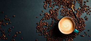 Bir fincan kapuçino ve kahve çekirdeği. Üst görünüm, siyah arkaplan, bedava kopya alanı. Robusta veya Arabica.