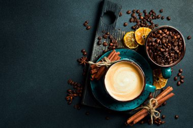 Bir fincan kapuçino ve kahve çekirdeği. Üst görünüm, siyah arkaplan, bedava kopya alanı. Robusta veya Arabica.