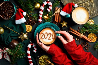 Elinde tarçınlı cappuccino tutan bir kadın. Numara 2024. Yeni yıl dekoru. Karanlık bir arka planda.