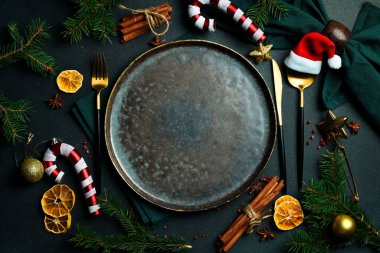 Şenlikli Noel sofrası. Masada şenlikli çatal bıçak takımı olan bir tabak. Bedava fotokopi. Üstteki görünüm Koyu bir arkaplanda.