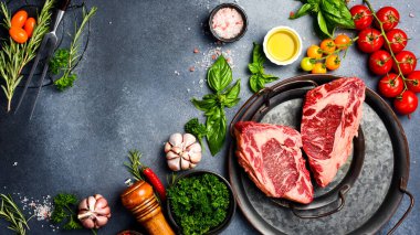 Çiğ Mermer Biftek. Gri taş bir masada biftek, baharat, baharat, tereyağı ve tuz pişirmek..