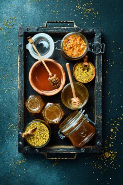 Bal seti, arı ürünleri ve bal peteği. Karanlık bir arka planda. Üst Manzara. Tahta bir kutuda..