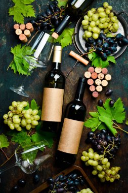 Taş bir masanın üzerinde şarap şişeleri, bardaklar, üzümler ve üzüm yapraklarının bileşimi. Üst Manzara. Metin için boş alan.