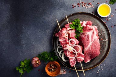 Soğan ve baharatla bir kasede kesilmiş çiğ domuz boynu. Salamura kebap. Gri taştan bir arka planda.