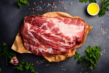 Parşömen kağıdının üzerinde pişmeye hazır bir parça domuz eti. Çiğ et. Gri taştan bir arka planda.