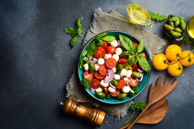 Taze yaz salatası: domates, mozzarella peyniri, fesleğen ve zeytin. Caprese. Gri beton arka planda.