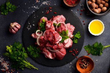 Çiğ domuz eti, siyah bir tabakta küp şeklinde kesilmiş. Et tabakları hazırlanıyor. Gri taştan bir arka planda.