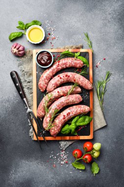 Biberiye ve baharatlı çiğ sığır eti sosisi ızgaraya hazır. Tahta kesme tahtasının üzerinde. Kapat..